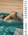 a girl with a beautiful tanned body having fun in the swimming pool of a luxury villa, the girl's butt is visible from under the water, azure water, splashes of water glow in the sun 142946715