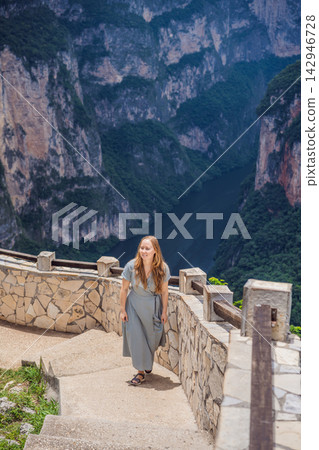 Woman tourist admiring the dramatic Sumidero Canyon viewpoint in Chiapas Mexico with steep canyon walls lush landscape river overlook nature tourism and standing at a viewpoint. Woman tourist admiring the dramatic Sumidero Canyon viewpoint in Chiapas Mexico with steep canyon walls lush landscape river overlook nature tourism and standing at a viewpoint. 142946728