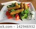 Close-Up of Crispy Fried Cheese Sticks on Fresh Mixed Salad with Dip 142946932