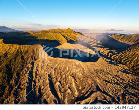 Golden sun bathes volcanic peaks in warm light Golden sun bathes volcanic peaks in warm light 142947127