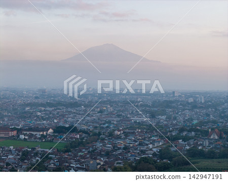 Misty mountain looms over sprawling cityscape Misty mountain looms over sprawling cityscape 142947191