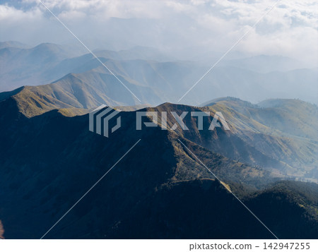 Layered mountain ridges stretch into misty distance Layered mountain ridges stretch into misty distance 142947255