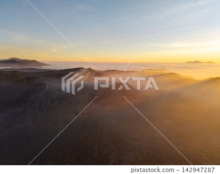 Golden dawn wraps volcanic peaks in misty embrace 142947287
