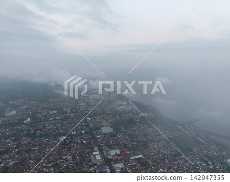Fog blankets coastal town, veiling distant horizon 142947355