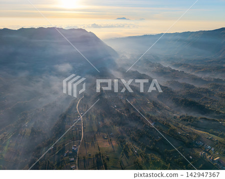 Mist swirls gently over rolling hills at dawn 142947367