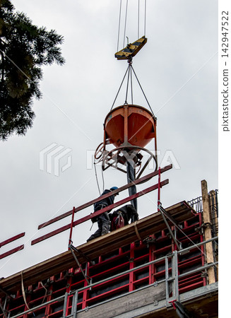 Workers Receiving Suspended Concrete Hopper at Height Workers Receiving Suspended Concrete Hopper at Height 142947522