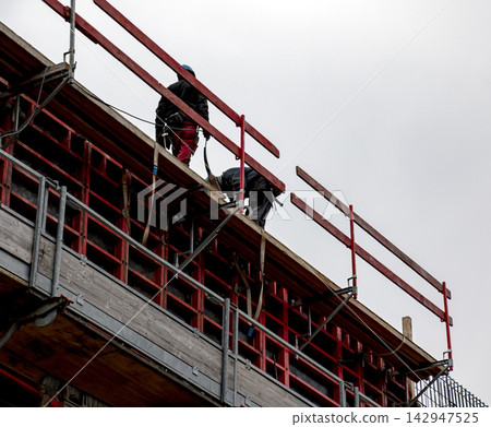 Construction Workers Handling Concrete Equipment on Upper Floor Construction Workers Handling Concrete Equipment on Upper Floor 142947525