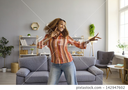 Happy woman dancing freely in bright modern living room at home indoors today Happy woman dancing freely in bright modern living room at home indoors today 142947602
