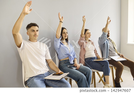Group of adults raising hands during interactive training seminar session Group of adults raising hands during interactive training seminar session 142947607