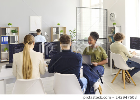 Developers collaborating in modern office, coding software on computers together Developers collaborating in modern office, coding software on computers together 142947608