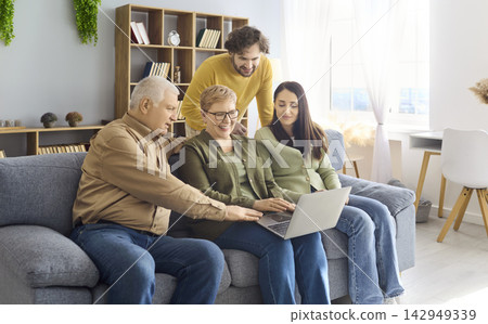 Happy multigenerational family with laptop at home, grandparents and parents Happy multigenerational family with laptop at home, grandparents and parents 142949339