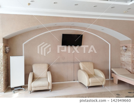 Modern interior design with beige armchairs and wall-mounted TV in a stylish living room Modern interior design with beige armchairs and wall-mounted TV in a stylish living room 142949660