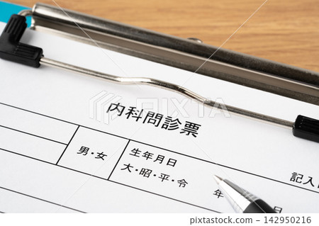 A medical questionnaire and a ballpoint pen clipped to a clipboard. A medical questionnaire and a ballpoint pen clipped to a clipboard. 142950216