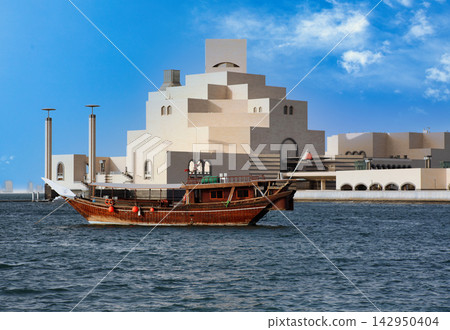 Traditional Dhow Boat Sailing Past the Museum of Islamic Art in Doha, Qatar Traditional Dhow Boat Sailing Past the Museum of Islamic Art in Doha, Qatar 142950404