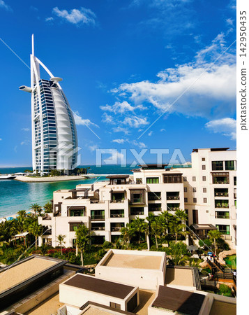 Burj Al Arab luxury hotel in Dubai, United Arab Emirates, with modern resort buildings and blue ocean under a clear sky. Burj Al Arab luxury hotel in Dubai, United Arab Emirates, with modern resort buildings and blue ocean under a clear sky. 142950435