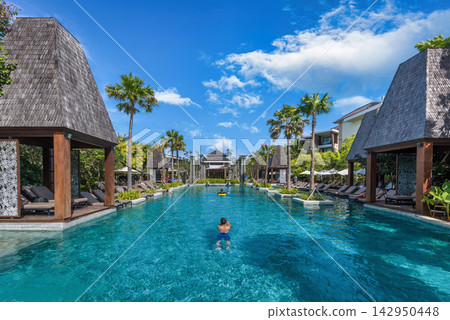 Luxury Resort Swimming Pool in Bali, Indonesia with Palm Trees and Blue Sky Luxury Resort Swimming Pool in Bali, Indonesia with Palm Trees and Blue Sky 142950448