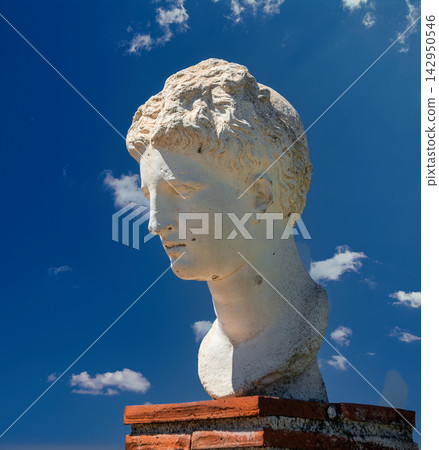 Ancient marble bust of a youth against a bright blue sky at the archaeological site of Butrint, Albania Ancient marble bust of a youth against a bright blue sky at the archaeological site of Butrint, Albania 142950546