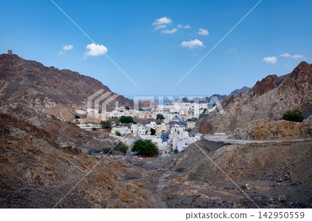 White buildings of a traditional village nestled in arid mountains near the coast of Muscat, Oman White buildings of a traditional village nestled in arid mountains near the coast of Muscat, Oman 142950559