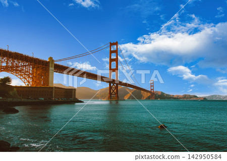 Golden Gate Bridge in San Francisco, California, spanning the bay under a blue sky with clouds. Golden Gate Bridge in San Francisco, California, spanning the bay under a blue sky with clouds. 142950584