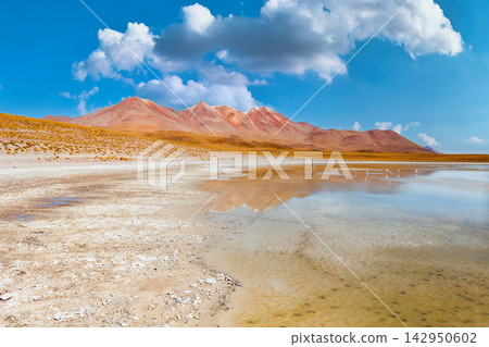 Vibrant Red Mountains Reflected in a Calm Lake Under a Blue Sky in Bolivia Vibrant Red Mountains Reflected in a Calm Lake Under a Blue Sky in Bolivia 142950602