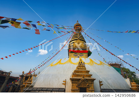 Boudhanath Stupa in Kathmandu, Nepal with colorful prayer flags under a clear blue sky Boudhanath Stupa in Kathmandu, Nepal with colorful prayer flags under a clear blue sky 142950686
