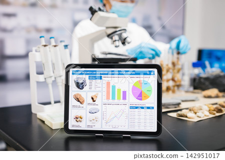 Tablet medical research data on a laboratory bench with microscope, pipettes, samples, and a scientist in blue gloves in the background Tablet medical research data on a laboratory bench with microscope, pipettes, samples, and a scientist in blue gloves in the background 142951017
