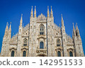 The beautiful facade and spire of Milan Cathedral stand out against the blue sky. 142951533