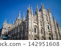 The magnificent Gothic architecture of Milan Cathedral, soaring against the blue sky. 142951608