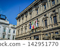 The imposing historical buildings of Milan and the Italian flag stand out against the blue sky. 142951770