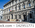 The imposing historical buildings of Milan and the Italian flag stand out against the blue sky. 142951771