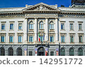 The imposing historical buildings of Milan and the Italian flag stand out against the blue sky. 142951772