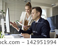 Team analysts discussing data dashboard on computer in bright modern office 142951994