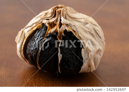 Aged black garlic with the skin peeled off to reveal the black flesh. Aged black garlic with the skin peeled off to reveal the black flesh. 142952697