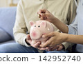 Hands placing coin in piggy bank, family savings for money management and wealth 142952740
