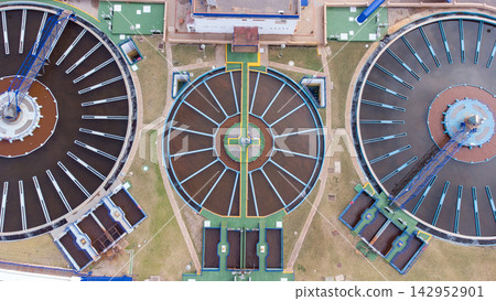 Aerial view of wastewater treatment plant with circular clarifiers, showcasing infrastructure, walkways, and operational facilities for urban water management solutions. 142952901