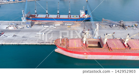Bustling cargo port with ships, cranes, and equipment at freight terminal. Calm waters showcase efficient maritime logistics and shipping industry operations. transportation and global trade concepts. 142952903