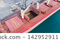 Impressive cargo ship at bustling port with open holds, cranes, and dock vehicles- dynamic scene of global trade and maritime logistics. 142952911