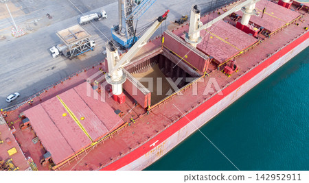 Impressive cargo ship at bustling port with open holds, cranes, and dock vehicles- dynamic scene of global trade and maritime logistics. Impressive cargo ship at bustling port with open holds, cranes, and dock vehicles- dynamic scene of global trade and maritime logistics. 142952911
