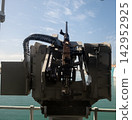 Mounted machine gun on naval platform guarding ocean horizon - military defense positioning. 142952925