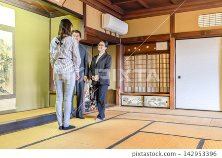 A male and female guide giving a tour of an old house, and a young female tourist. A male and female guide giving a tour of an old house, and a young female tourist. 142953396