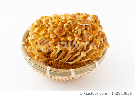 Fresh brown enoki mushrooms served on a bamboo basket against a white background. Fresh brown enoki mushrooms served on a bamboo basket against a white background. 142953636