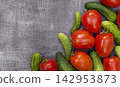 Fresh tomatoes and cucumbers displayed on wood, suitable for seasonal harvest, vegetarian food, recipes, and commercial. 142953873