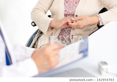Senior woman conducting a medical examination; face-to-face; medical; hands Senior woman conducting a medical examination; face-to-face; medical; hands 142954763