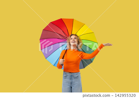 A girl smiles while holding a vibrant umbrella under clear skies A girl smiles while holding a vibrant umbrella under clear skies 142955320