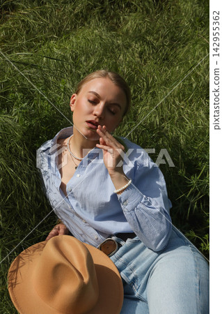 Model relaxes in grass and enjoys a snack outdoors in daylight Model relaxes in grass and enjoys a snack outdoors in daylight 142955362
