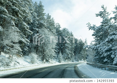 Winter. Curved road surrounded by frosty trees in serene winter setting Winter. Curved road surrounded by frosty trees in serene winter setting 142955393