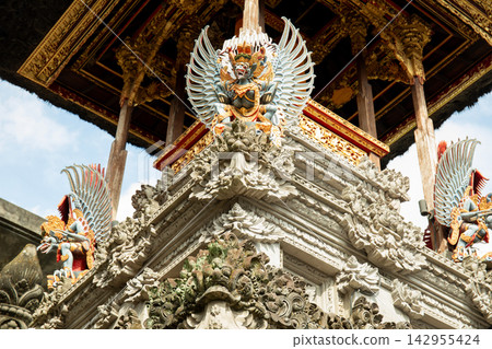 Temple features ornate carvings and colorful sculptures against clear sky Temple features ornate carvings and colorful sculptures against clear sky 142955424