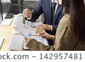 Colleagues analyzing financial charts together at desk during office planning 142957481