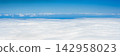 Panoramic view above a vast sea of white clouds under a clear blue sky with layered cloud formations stretching to the horizon 142958023