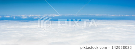 Panoramic view above a vast sea of white clouds under a clear blue sky with layered cloud formations stretching to the horizon 142958023